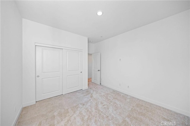 unfurnished bedroom featuring a closet and light colored carpet