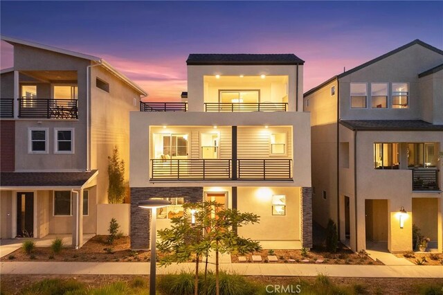 back house at dusk featuring a balcony