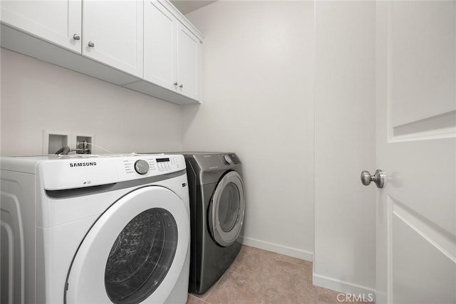 laundry area featuring light tile patterned floors, washer and clothes dryer, and cabinets