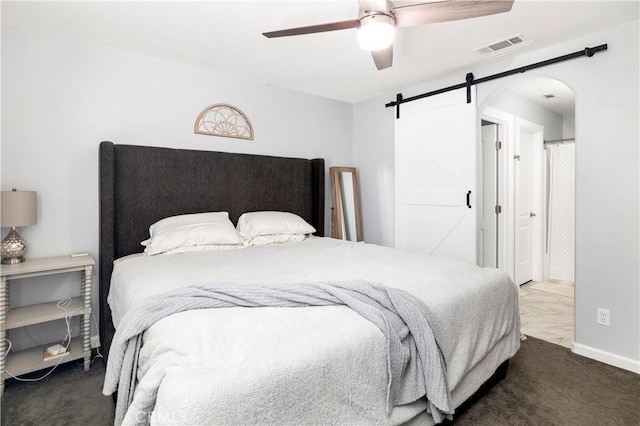 bedroom with ceiling fan, a barn door, and carpet