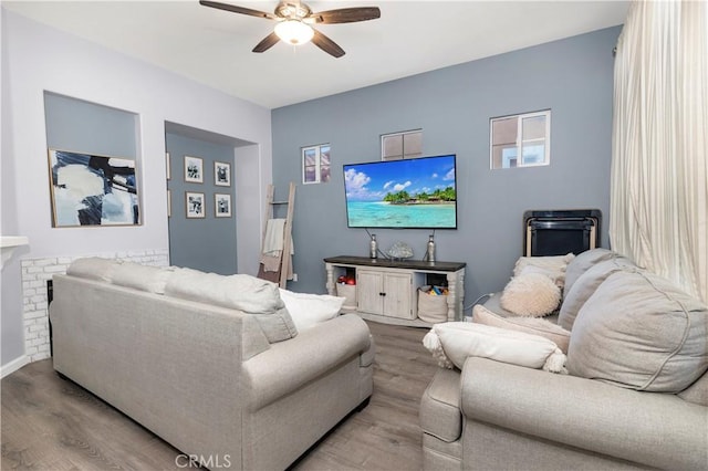 living room with ceiling fan, a fireplace, and light wood-type flooring