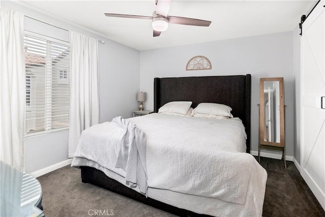 bedroom with a barn door, ceiling fan, and dark colored carpet