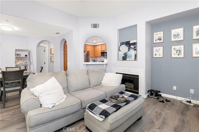 living room with a brick fireplace and light hardwood / wood-style flooring