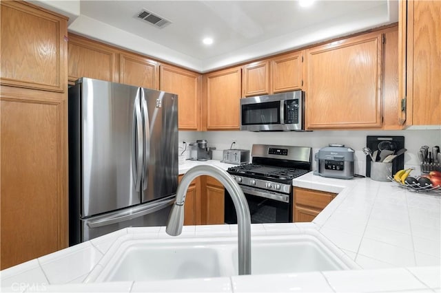 kitchen with stainless steel appliances, sink, and tile counters