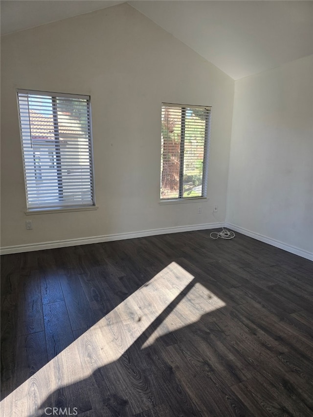 empty room with plenty of natural light, dark hardwood / wood-style floors, and lofted ceiling