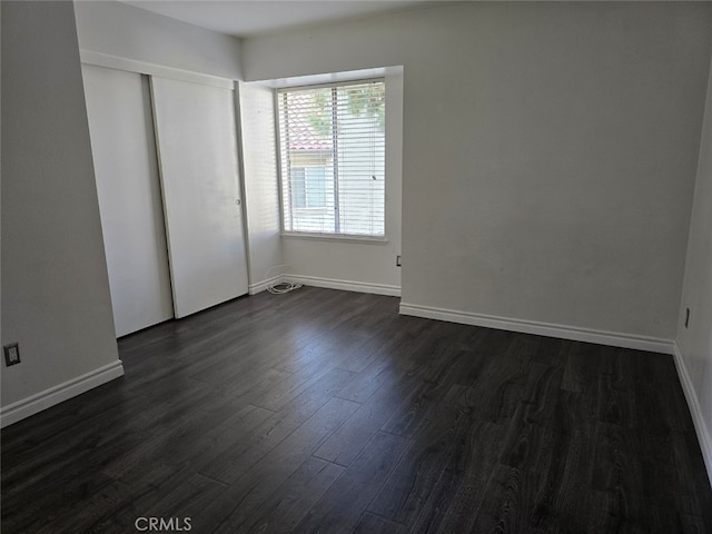 unfurnished bedroom with dark wood-type flooring and a closet