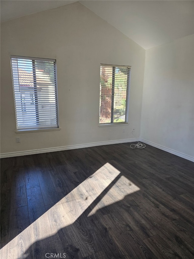 empty room featuring plenty of natural light, lofted ceiling, and dark hardwood / wood-style flooring