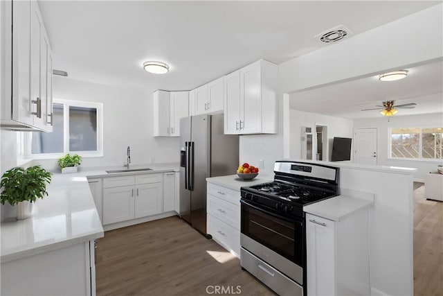 kitchen with sink, white cabinets, dark hardwood / wood-style flooring, kitchen peninsula, and stainless steel appliances