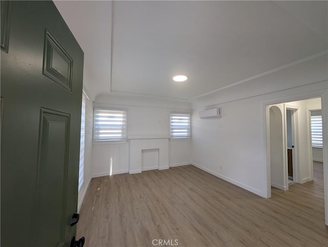 spare room featuring a wall mounted air conditioner, light hardwood / wood-style flooring, and plenty of natural light