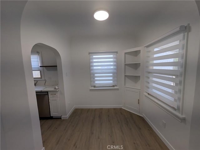 unfurnished dining area featuring built in shelves, dark hardwood / wood-style floors, and a healthy amount of sunlight