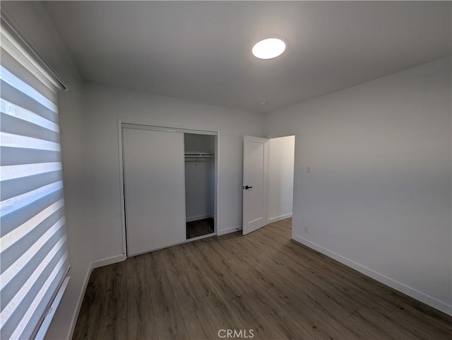 unfurnished bedroom with dark hardwood / wood-style floors and a closet