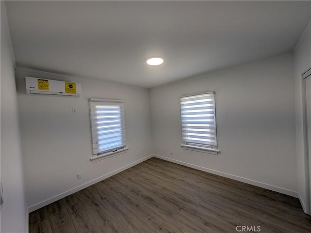 unfurnished room with dark wood-type flooring and a wall unit AC