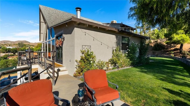 back of property with a mountain view, a yard, and a patio