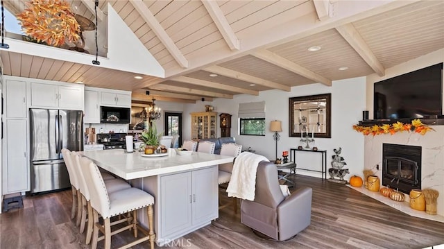 kitchen with stainless steel refrigerator, a center island, white cabinets, a kitchen bar, and dark hardwood / wood-style flooring