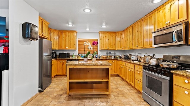 kitchen with stainless steel appliances, a center island, and stone countertops