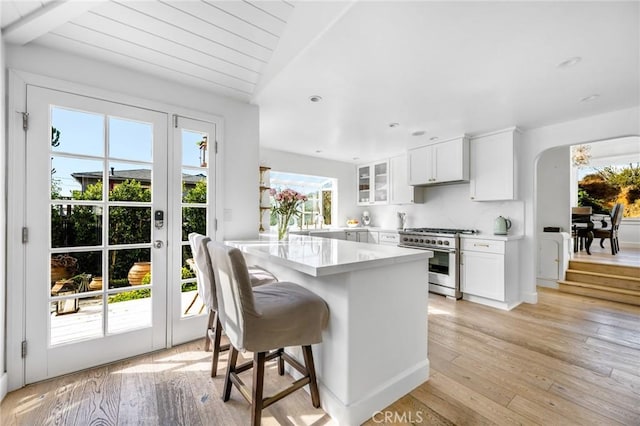 kitchen featuring white cabinetry, a kitchen breakfast bar, stainless steel stove, and light wood-type flooring