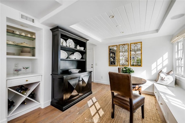 dining space with light hardwood / wood-style flooring, wooden ceiling, and a raised ceiling