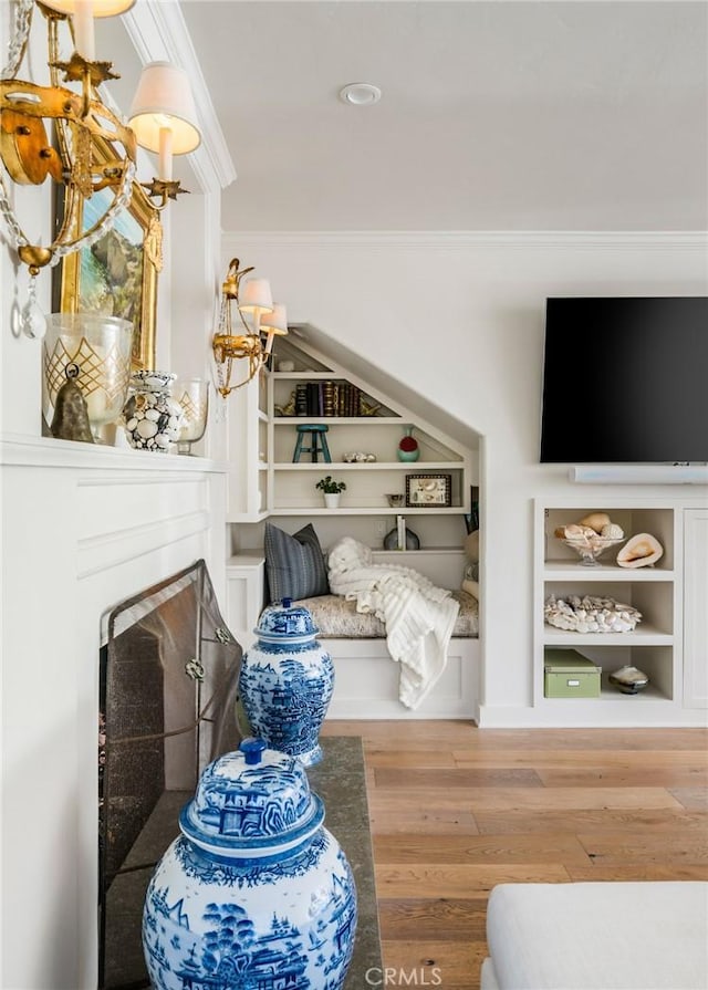 living room featuring crown molding, wood-type flooring, and built in shelves