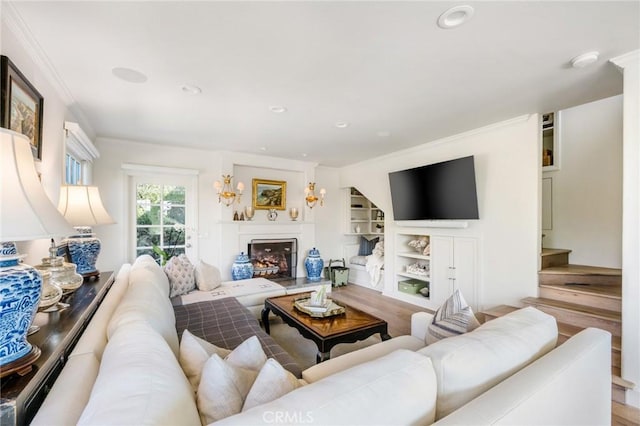 living room with ornamental molding, hardwood / wood-style floors, and built in shelves