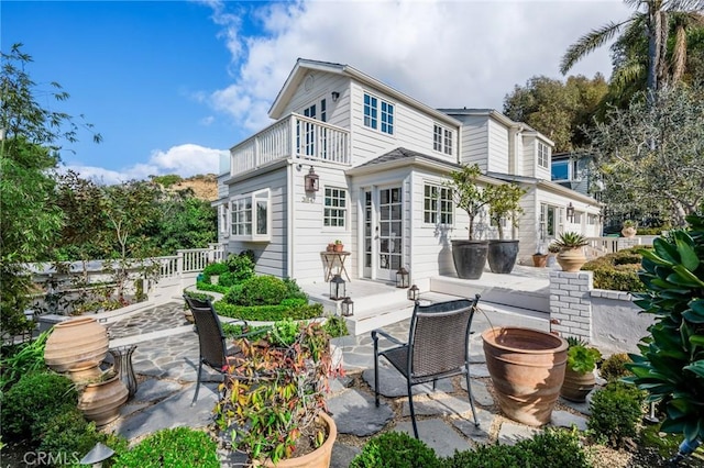 rear view of property featuring a patio, a balcony, and french doors