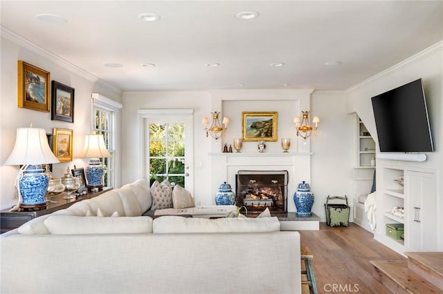 living room with built in features, light hardwood / wood-style flooring, and ornamental molding