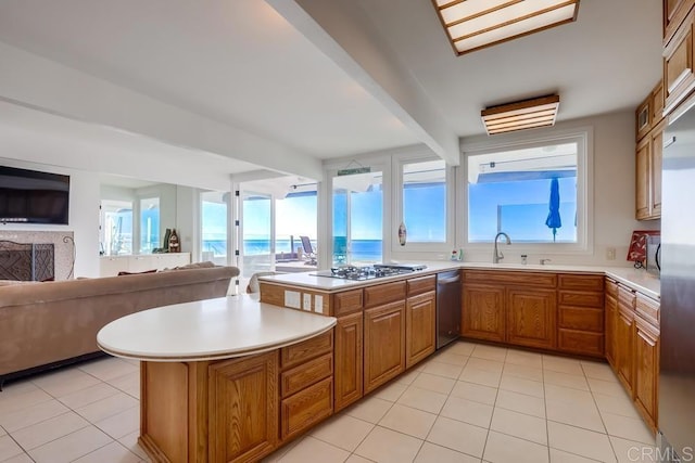 kitchen with light tile patterned flooring, sink, kitchen peninsula, stainless steel appliances, and a water view