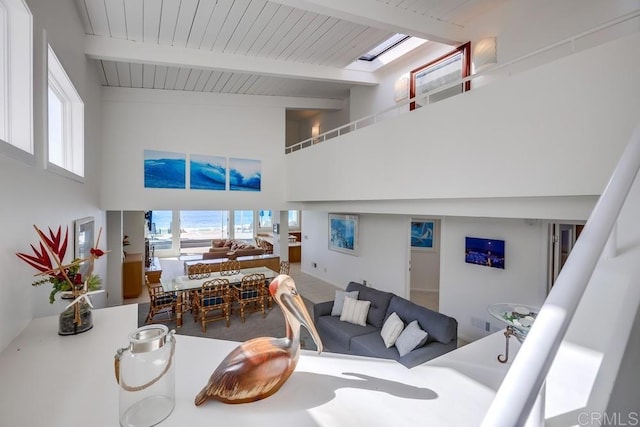 living room with wood ceiling, beam ceiling, a skylight, and high vaulted ceiling