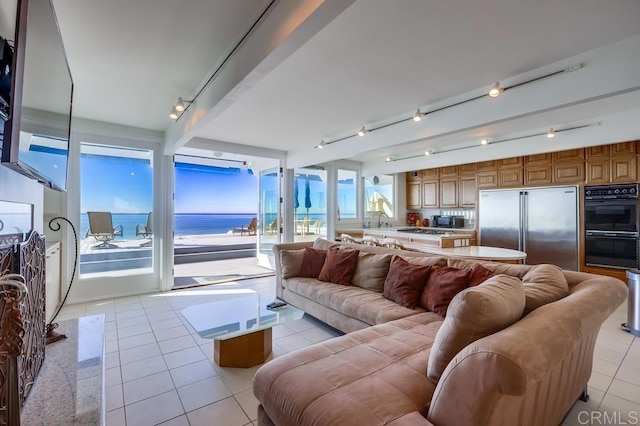 tiled living room featuring a water view and sink