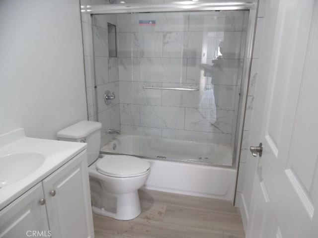 full bathroom with hardwood / wood-style flooring, enclosed tub / shower combo, vanity, and toilet