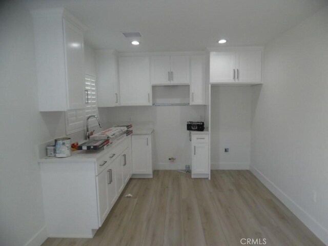 kitchen with light hardwood / wood-style flooring and white cabinets