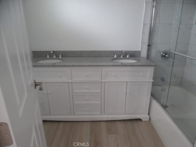 bathroom with enclosed tub / shower combo, vanity, and hardwood / wood-style floors