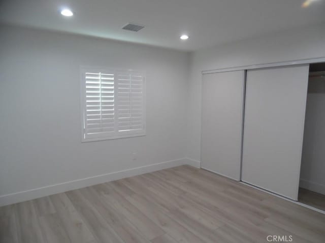 unfurnished bedroom featuring light hardwood / wood-style floors and a closet