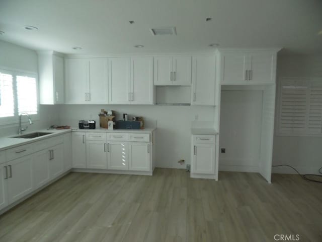 kitchen featuring white cabinetry, sink, and light wood-type flooring