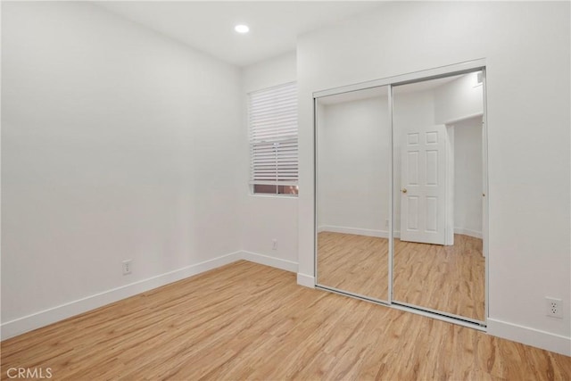 unfurnished bedroom with light wood-type flooring and a closet