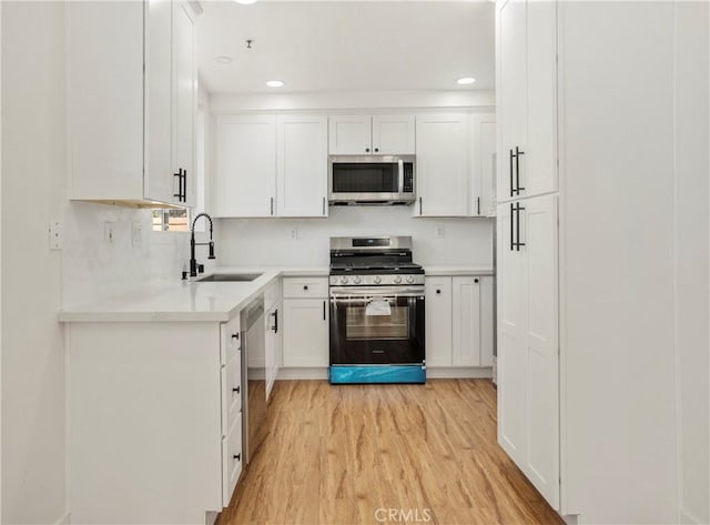 kitchen featuring stainless steel appliances, white cabinetry, sink, and light wood-type flooring