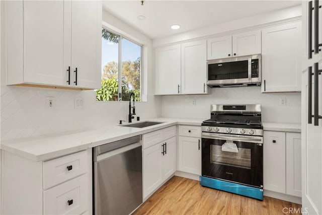 kitchen with white cabinetry, sink, light wood-type flooring, and appliances with stainless steel finishes