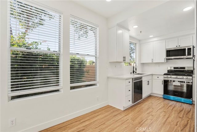 kitchen with stainless steel appliances, sink, white cabinets, and light wood-type flooring