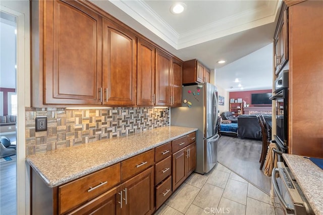 kitchen with light stone counters, backsplash, crown molding, and stainless steel refrigerator