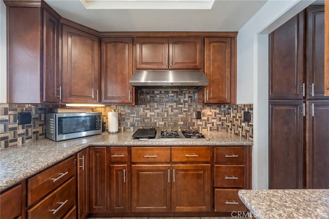 kitchen with light stone countertops, decorative backsplash, and stainless steel appliances