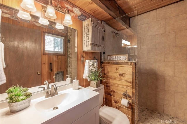 bathroom with a tile shower, wood walls, beamed ceiling, vanity, and wooden ceiling