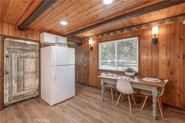 kitchen featuring beamed ceiling, white cabinetry, white fridge, and wooden walls