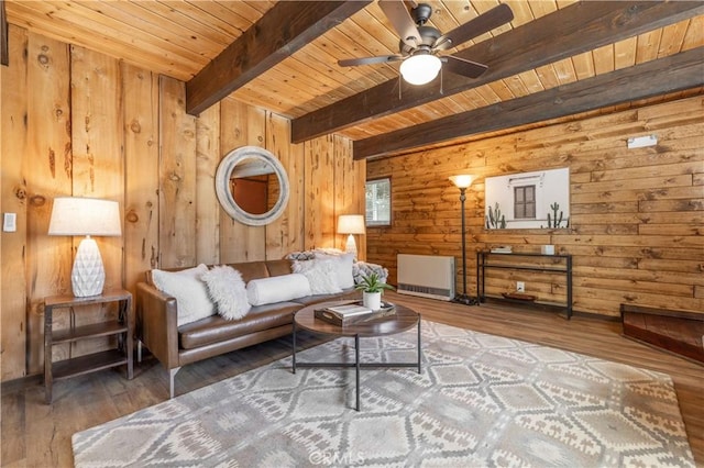 living room featuring wood walls, wooden ceiling, hardwood / wood-style flooring, ceiling fan, and beam ceiling