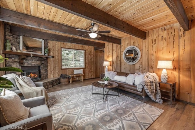 living room with wood ceiling, light wood-type flooring, wooden walls, beamed ceiling, and a fireplace