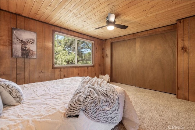 carpeted bedroom with wood ceiling, ceiling fan, and wood walls