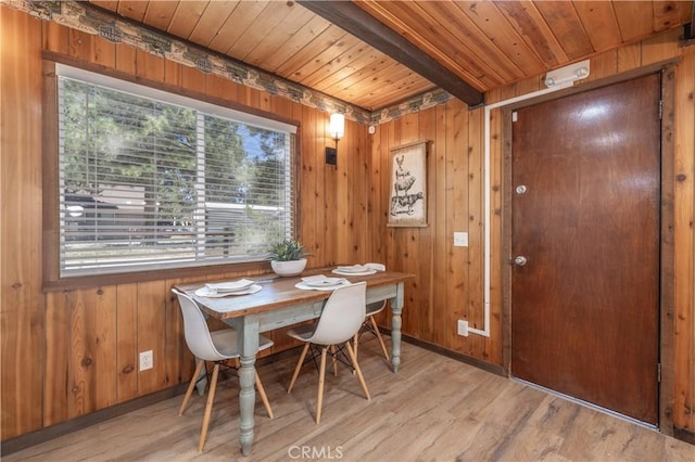 dining room with wood ceiling, wood walls, beamed ceiling, and light wood-type flooring