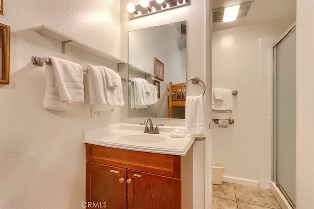 bathroom with a shower with door, vanity, and tile patterned floors