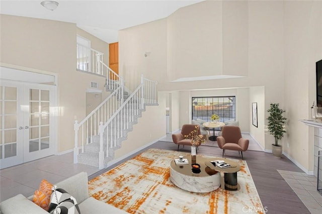 living room with a towering ceiling, hardwood / wood-style floors, a fireplace, and french doors