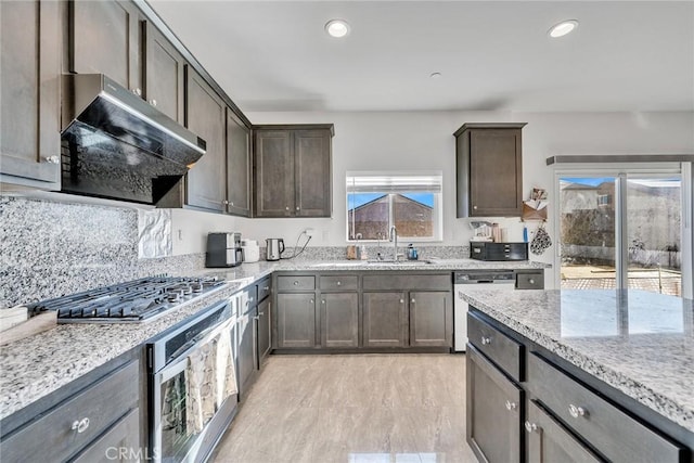 kitchen featuring sink, dark brown cabinets, stainless steel appliances, light stone counters, and tasteful backsplash