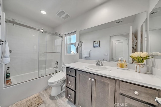 full bathroom with toilet, vanity, and bath / shower combo with glass door