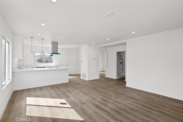 unfurnished living room with plenty of natural light, sink, and hardwood / wood-style floors